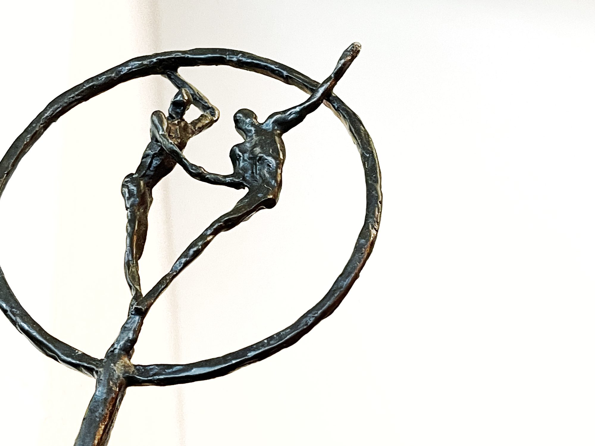 Bronzen beeldje van twee figuren binnen een cirkel